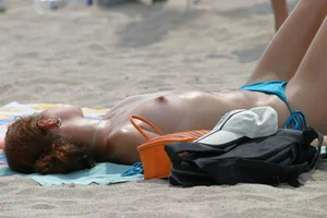 Flat topless candid girl lying on the public beach