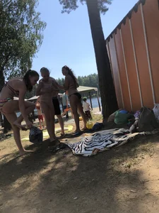 Young Skinny Girl Taking Off Her Denim Shorts Leaving a Swimsuit - Bending Over While Laying a Blanket on the Ground at a Lake Nature Park Gallery