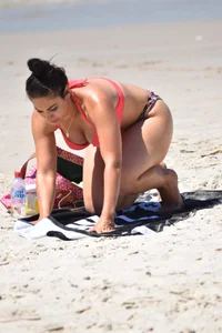 Huge boobed thick brunette babe on the beach in a bikini