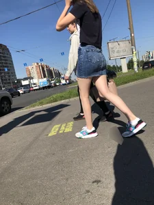 Cute Girl in a Short Denim Skirt Walking on a Street And Waiting on a Crosswalk Gallery