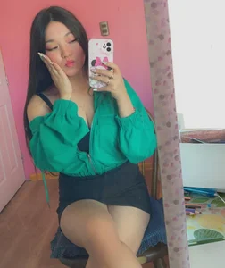 Sweet Asian Girl in a Short Skirt Sitting With Crossed Legs Mirror Selfie