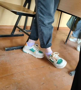College teen's feet in white socks and sneakers closeup in class