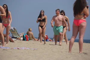 Sexy brunette in bikini playing football on the beach
