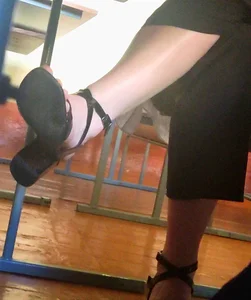College girl's legs closeup in classroom, high-heeled sandals and pantyhose