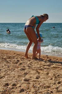Sexy blonde milf on the beach in blue thong bikini and showing nice camel toe