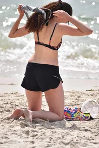 Brunette girl in black shorts and bikini top on the beach