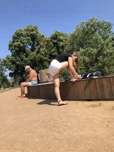Cute girl in white mini shorts fixing her sandal at the beach creepshot