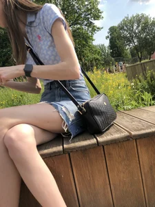 A Very Skinny Girl in Torn Shorts Sitting on a Bench With Crossed Legs in a Park