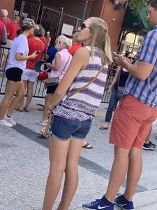 Bunch of girls in various outfits at a Cardinals baseball game