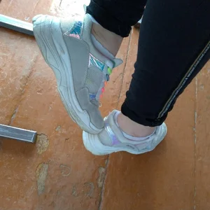 Closeups of college teen's feet in sneakers and socks in classroom