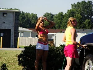 Group of cute girls at a car wash in bikinis and shorts