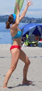 Skinny mature lady in red bikini bottom on the beach playing volleyball