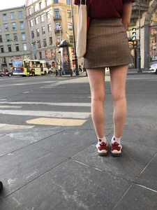 Candid cutie wearing a short skirt standing on crosswalk, closeups of slim legs