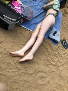 Cute Candid Girl in a Green Swimsuit With Pale Skin Lying on the Beach