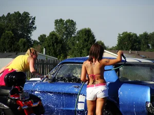 Group of cute girls at a car wash in bikinis and shorts