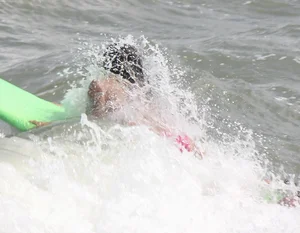 Brunette bikini girl on the beach and surfing in her bikini