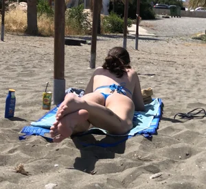 Hot skinny girl chilling on the beach wearing a swimsuit