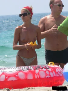 Topless skinny blonde lady in a g-string bikini at the beach