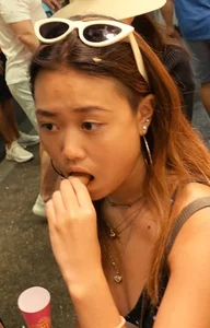 Cute Asian girl stuffing her mouth street photo