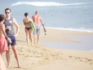 Mature short haired brunette surfer looking sexy on the beach