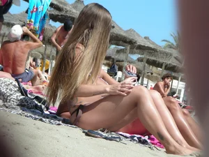 Tattooed babe at the beach with a nice round ass in little thong bikini
