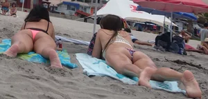 Pink and patterned bikini girls' asses laying on the beach