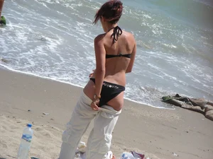 Sexy girl in black bikini dressing on the beach
