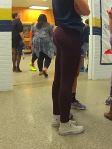 Skinny college teen in leggings bending over a drinking fountain