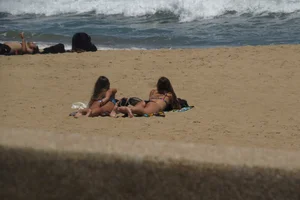 Two babes laying on the beach in bikinis with nice asses