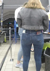 Two hot milfs in tight blue jeans standing at the cash register at the supermarket, awesome big butts