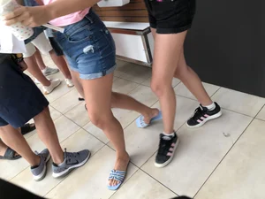 Two skinny teens in shorts at food court, nice skinny legs