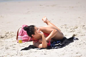 Huge boobed thick brunette babe on the beach in a bikini