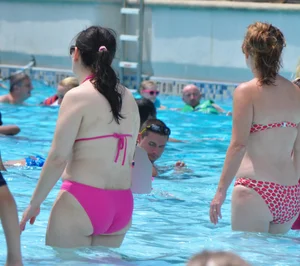 Thick brunette lady in the pool in a pink bikini