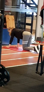 Girl in Grey Tights Standing Doggy Style on Her Yoga Mat Working Out at a Gym Creepshot