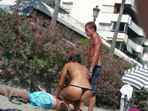 Sexy girl on the beach getting some sun in a little black thong bikini