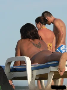 Topless tattooed lady on the beach with fake big tits