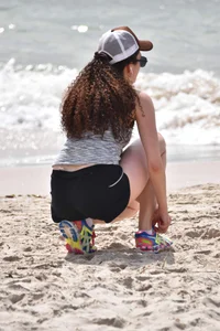 Brunette girl in black shorts and bikini top on the beach