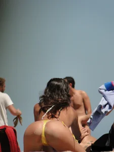 Topless lady on the beach in a gold thong with a nice ass