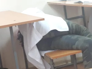 College Teen in Camouflage Pants Lying on the Classroom Bench Creepshot
