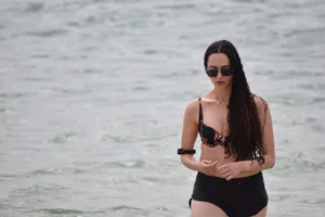 Brunette girl in black shorts and bikini top on the beach