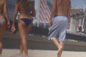 Two sexy friends, one blonde and one brunette, on the beach in bikinis