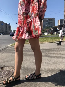 Hot street candid girl wearing a short dress and sandals standing on the crosswalk, wind is playing with her hair