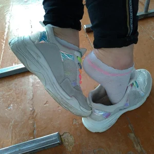 Closeups of college teen's feet in sneakers and socks in classroom