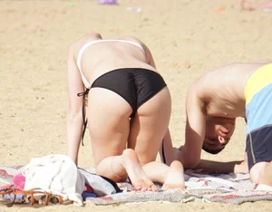 Sexy girl on the beach laying out and bending over in her bikini