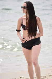 Brunette girl in black shorts and bikini top on the beach
