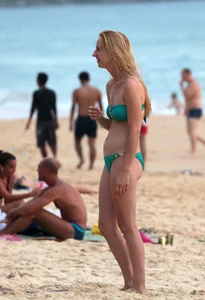 Sexy brunette in thong bikini and blonde friend in green bikini at the beach