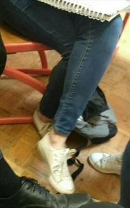 Crossed legs of a college girl sitting in classroom: wearing tight blue jeans