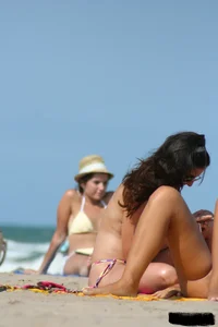 2 topless girls at the beach in thongs
