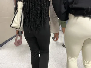 Two college teens wearing tight pants walking down the hallway