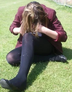 Young girl in black pantyhose sitting on the grass candid photo